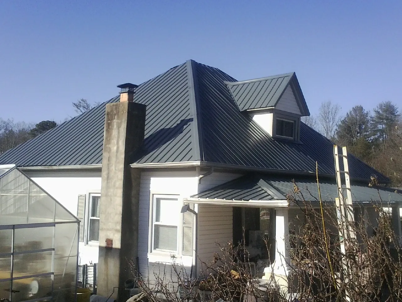 Dark blue standing seam metal roof on a white farmhouse with dormer — Slate & Tile Roof Repair by Roofing Brothers in Dravosburg