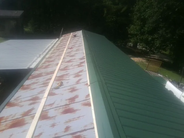 Old rusted panels beside newly installed green metal roofing — Wind Damage Roof Repair by Roofing Brothers in Dravosburg