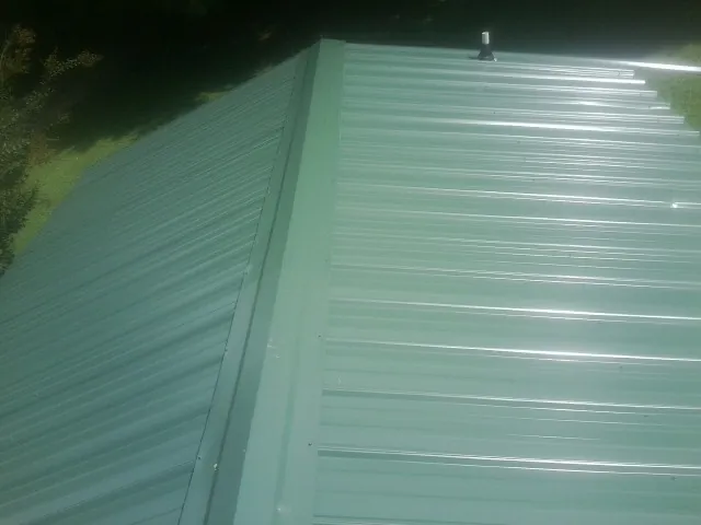 New green metal panels meeting at the ridge of a roof — Flat Roof Repair work by our crew in Dravosburg