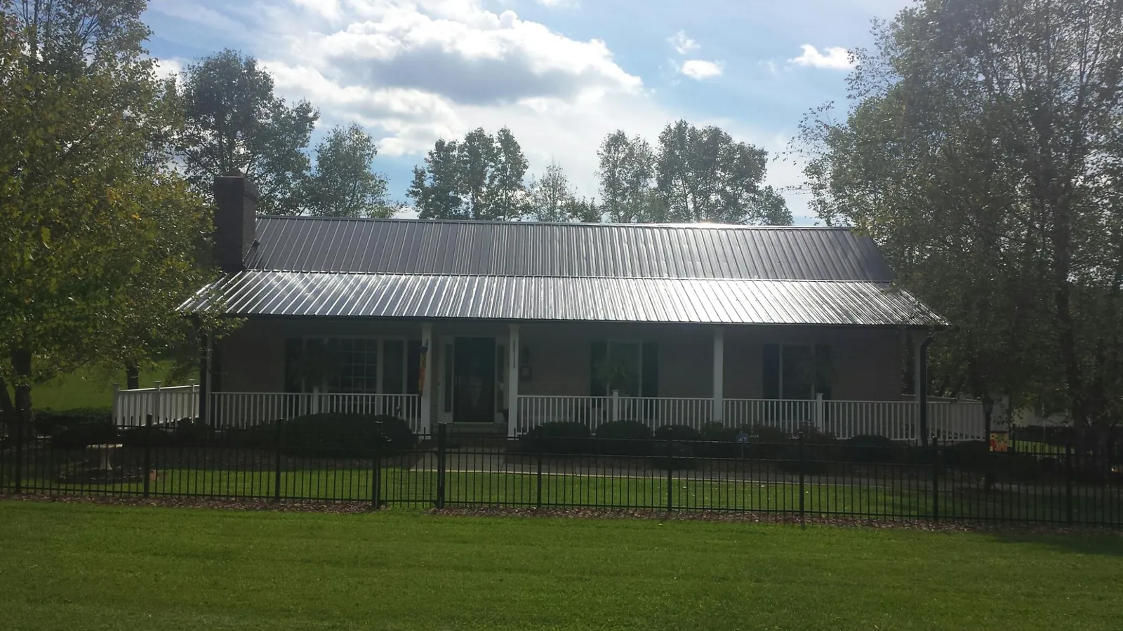 Gray metal roof on a brick ranch with a full width front porch — Gutter Guard Installation work by our crew in Dravosburg