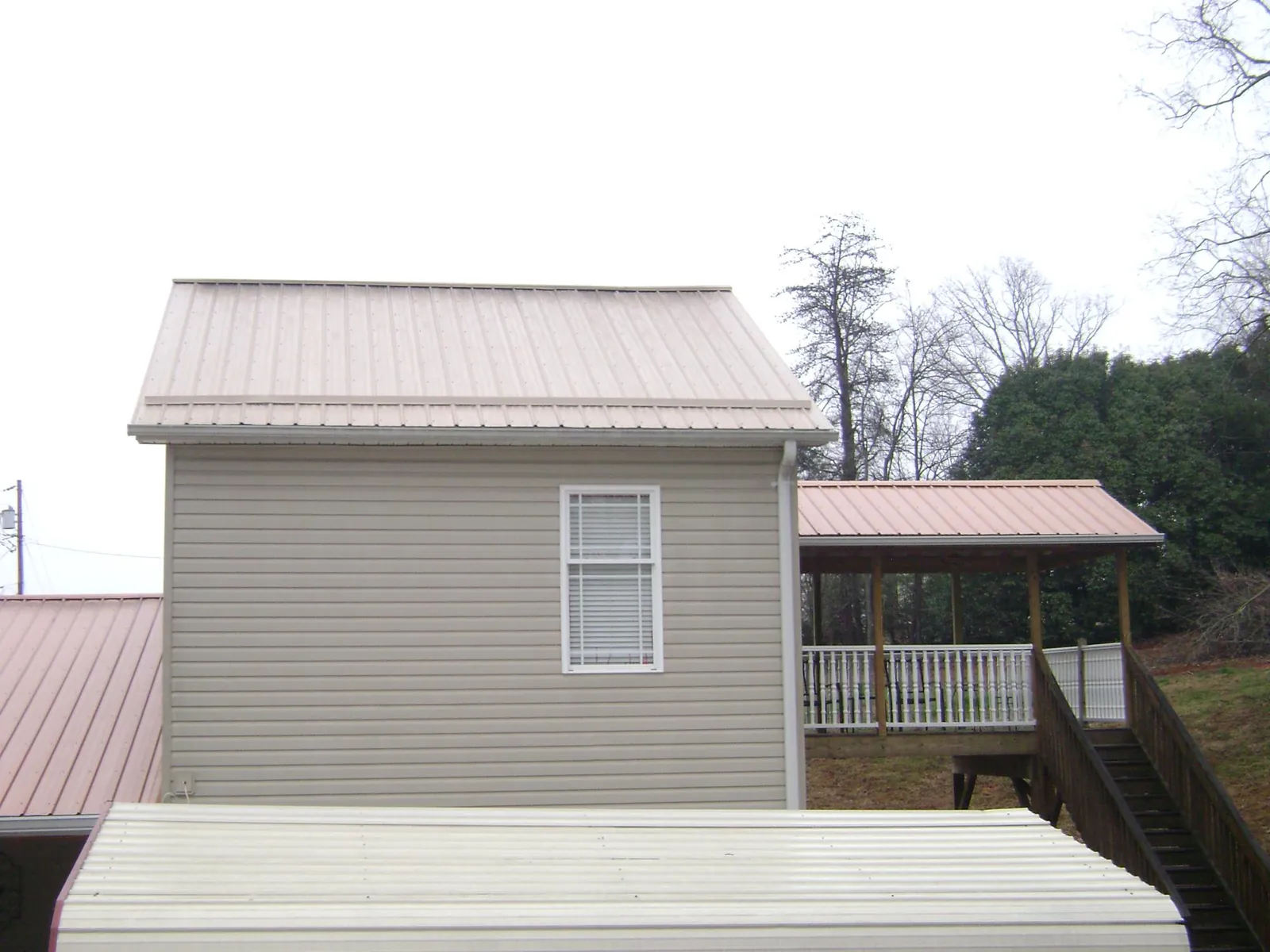 Tan metal roofs on a two story addition and attached porch, from a Roof Replacement job in Dravosburg