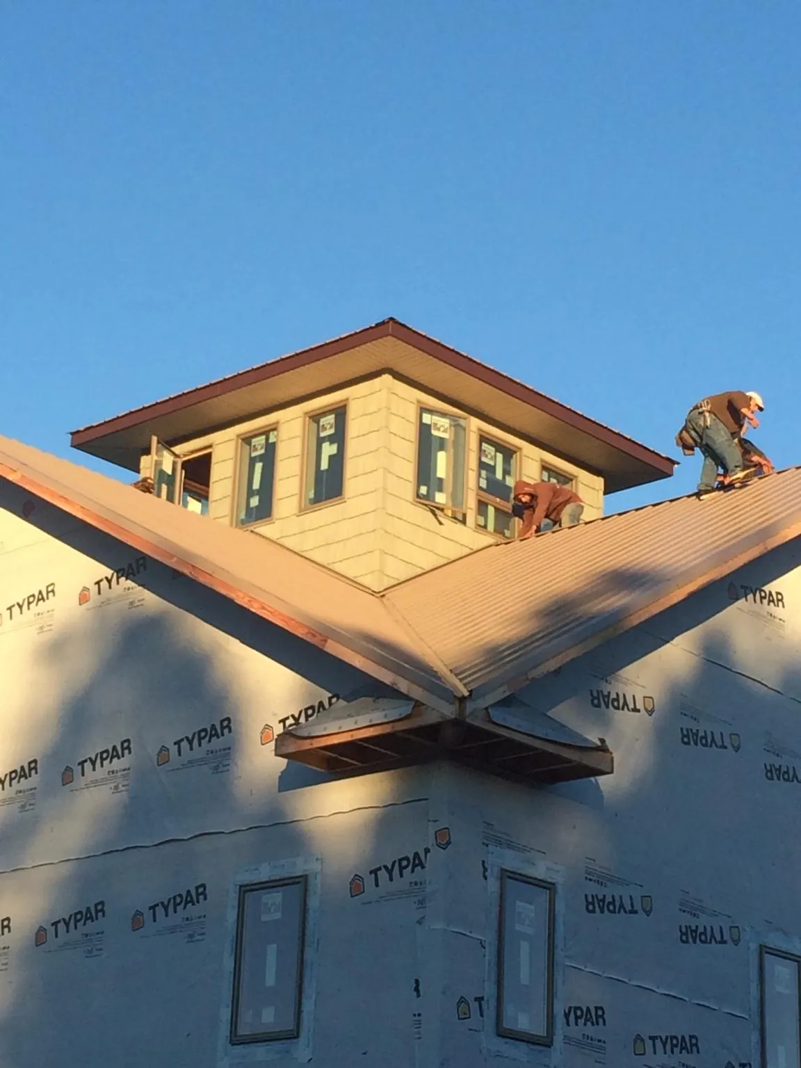 Roofers working around a rooftop cupola on a new metal roof at sunset — Roof Waterproofing in Dravosburg by Roofing Brothers